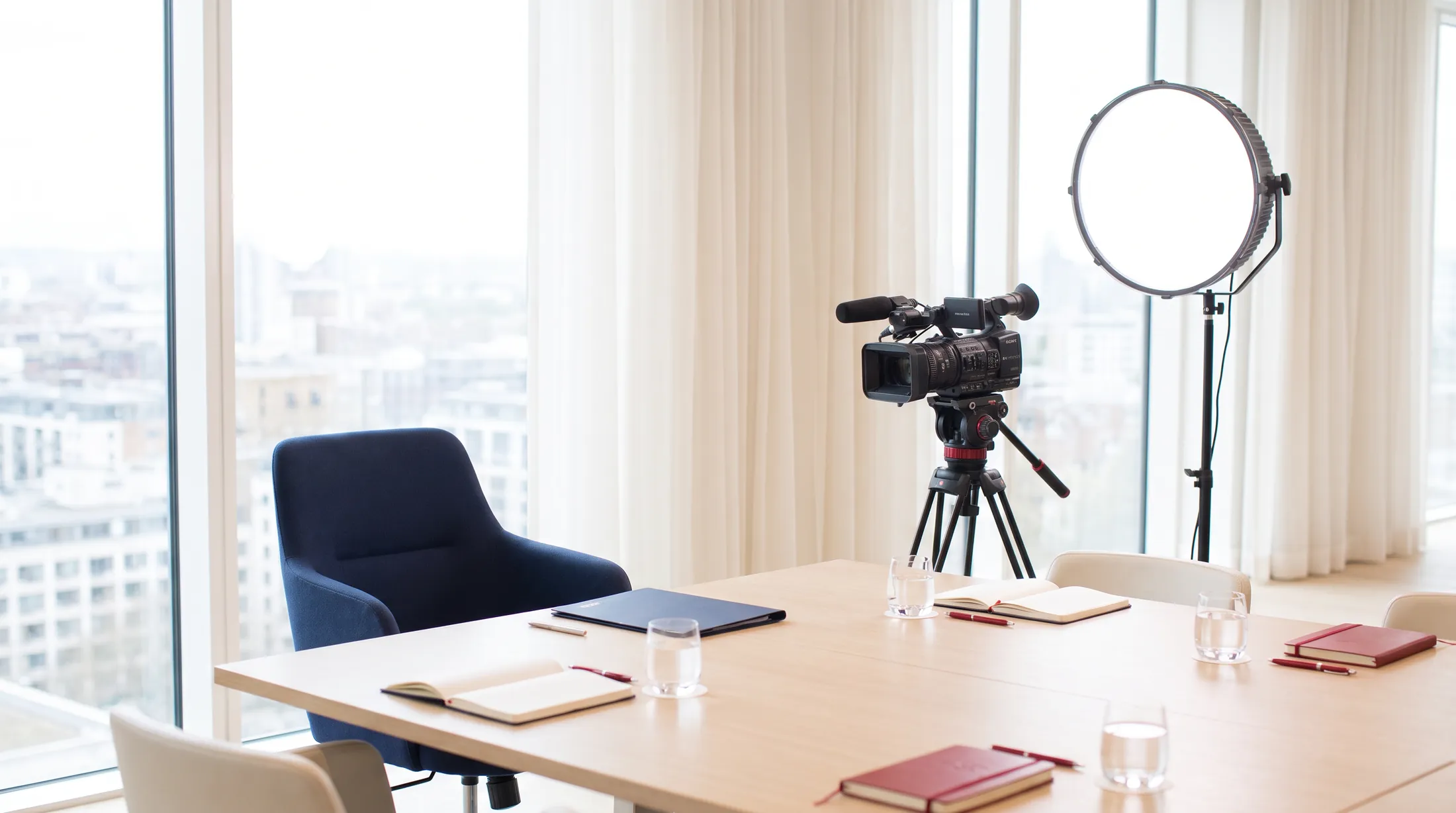 O sală de consiliu pregătită pentru media training, cu o cameră video pe trepied